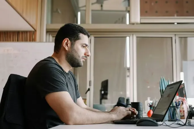 Male writer using rewording tool on computer.