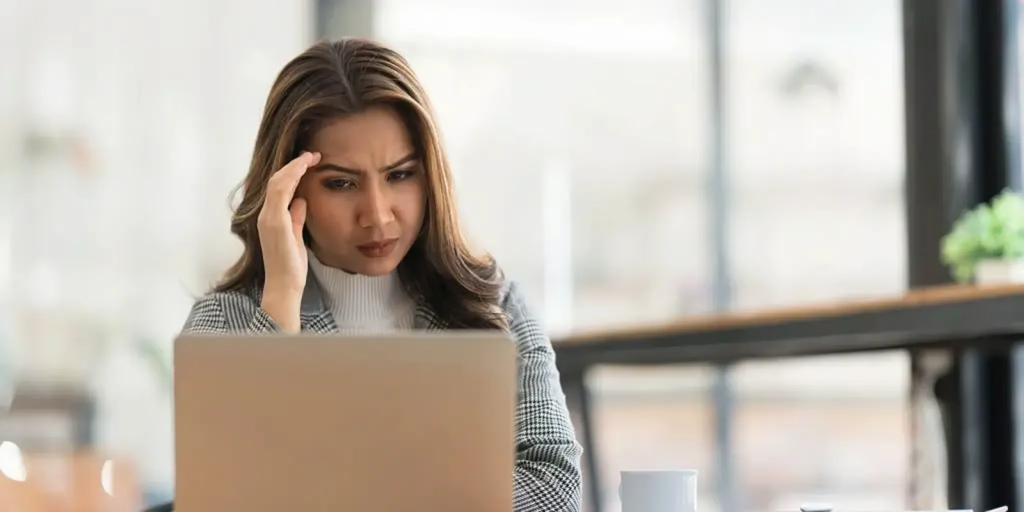 Concerned woman looking at a laptop while working.