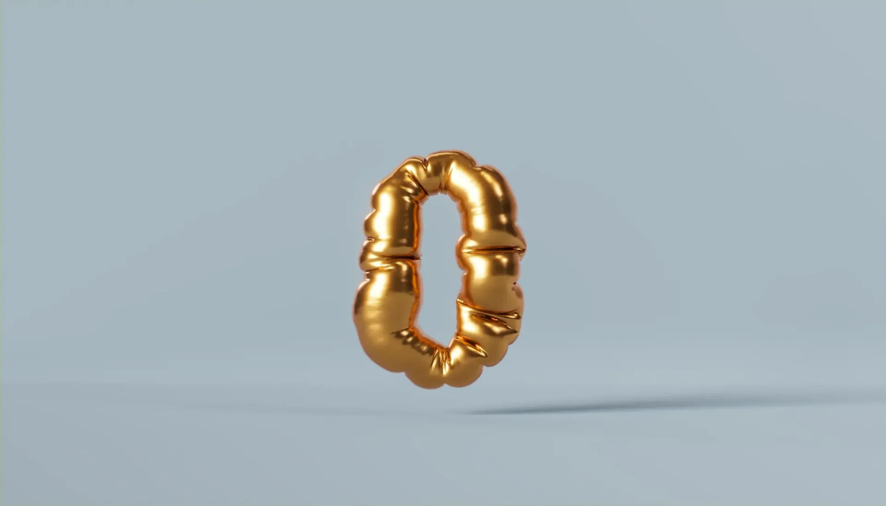 Gold balloon shaped like the number zero floating against a light background.
